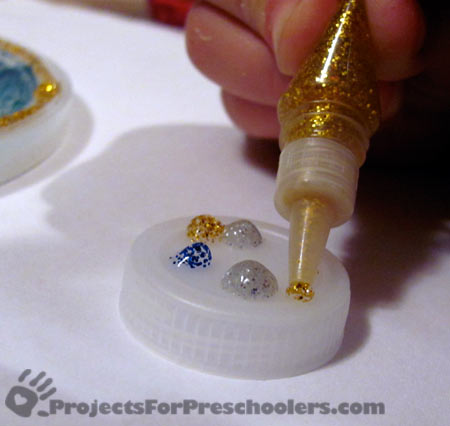 Apply glitter glue to plastic lid and let dry